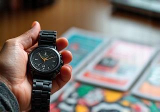 Hand holding a stopwatch beside printed flyers